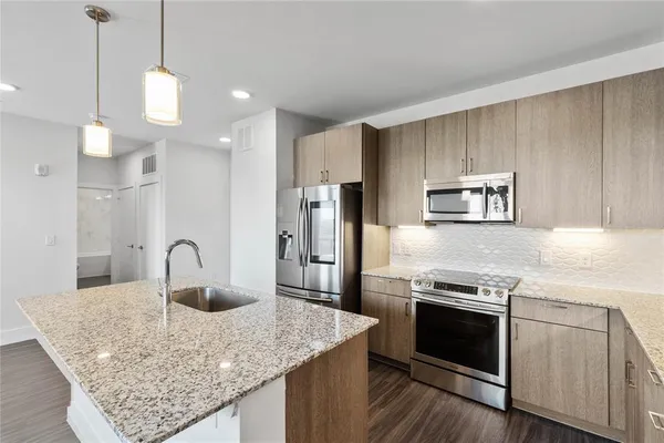 a kitchen with stainless steel appliances granite countertop a sink a stove and refrigerator