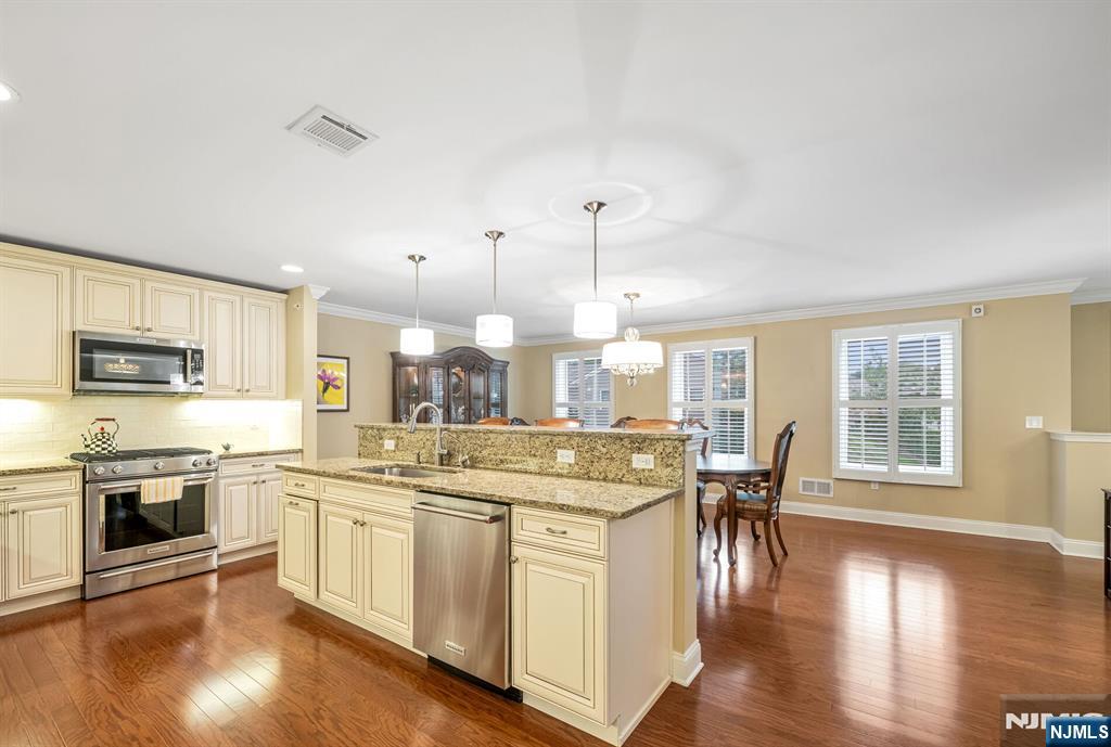 1508 Whitney Lane, Unit 1508 Allendale, NJ 07401 - Photo 8 of 24 a kitchen with stainless steel appliances granite countertop a stove top oven a sink a dining table and chairs with wooden floor