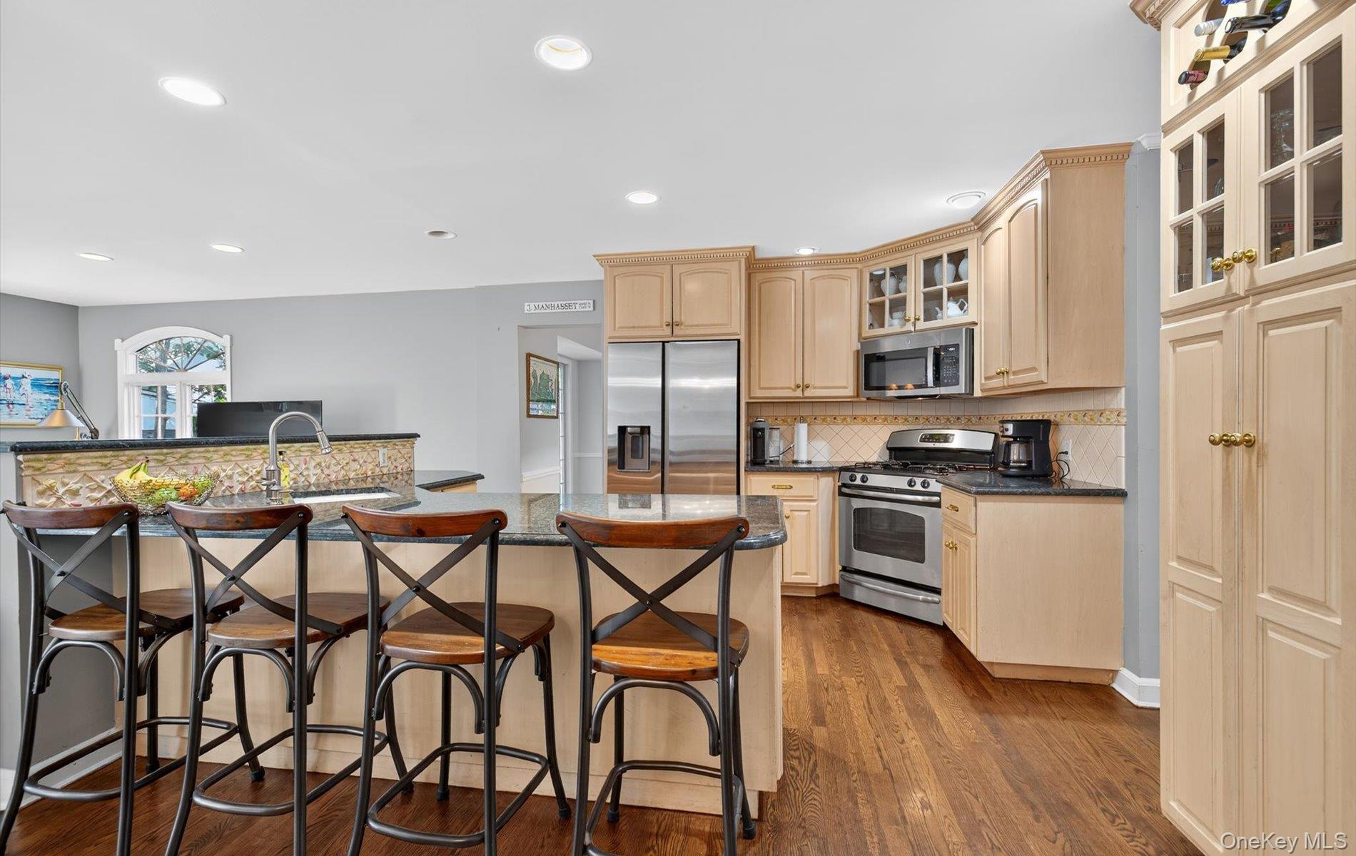 53 Eakins Road Manhasset, NY 11030 - Photo 8 of 34 a kitchen with stainless steel appliances kitchen island granite countertop a stove a sink and a refrigerator