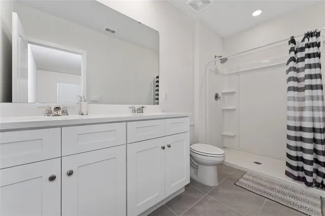 a bathroom with a double vanity sink toilet and shower