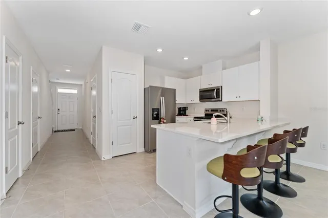 a room with stainless steel appliances kitchen island granite countertop a sink and cabinets