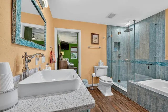 a bathroom with a bathtub shower sink mirror and toilet