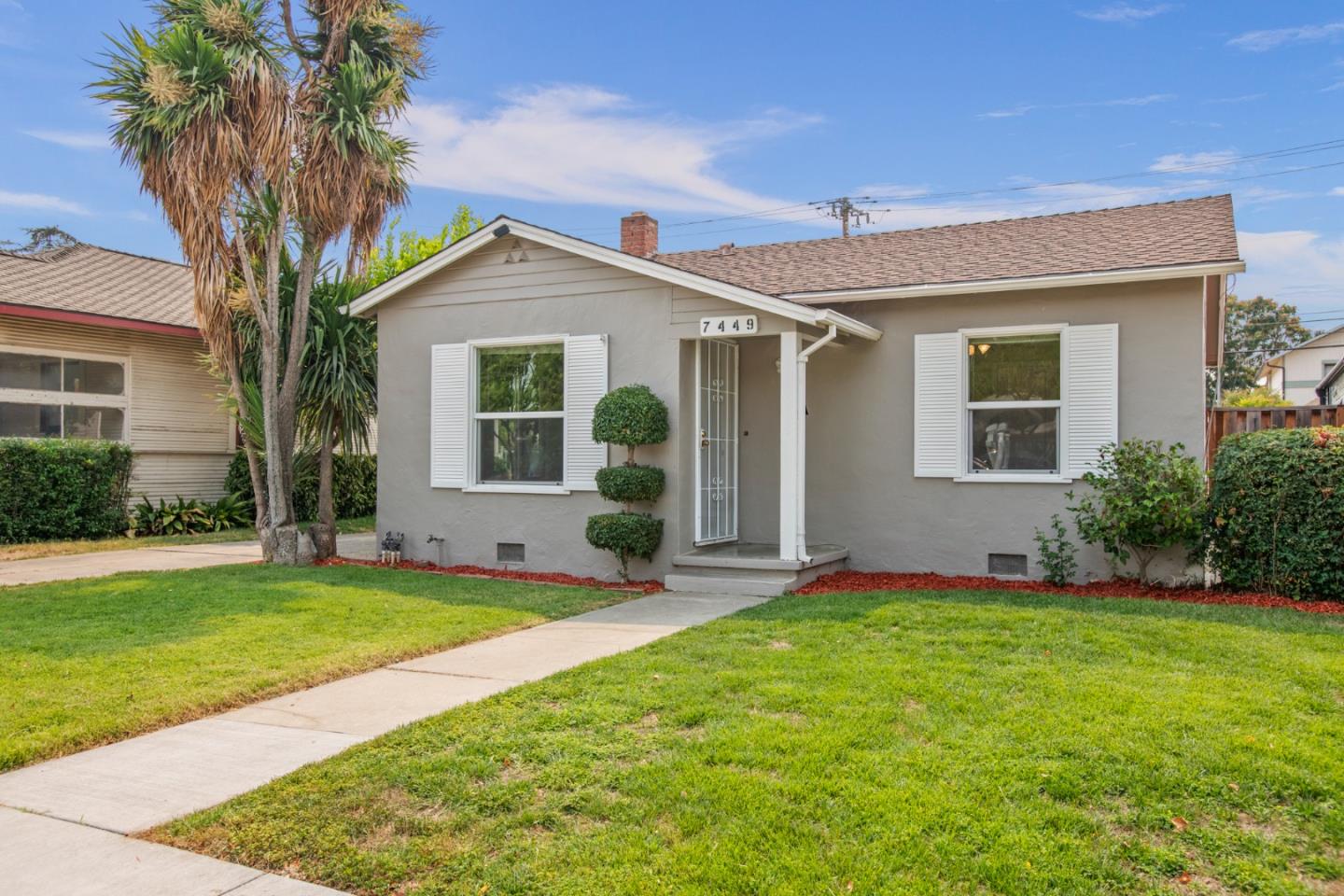 a view of a house with a yard and potted plants