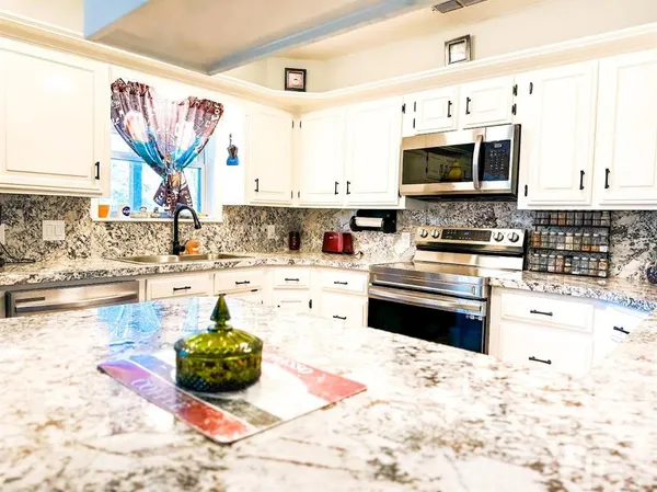 a kitchen with stainless steel appliances kitchen island granite countertop a stove a sink and a microwave