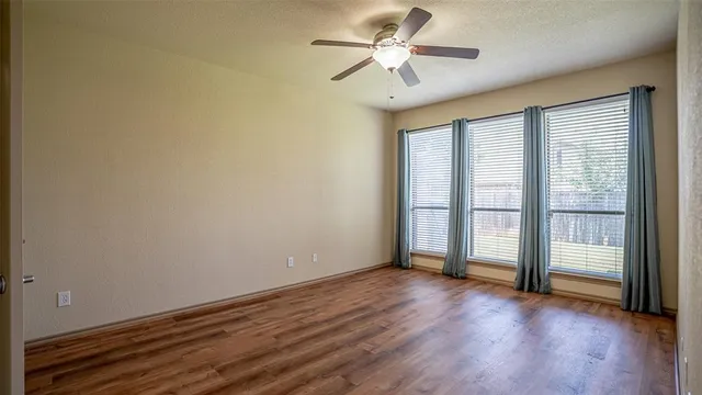 a view of an empty room with a window and wooden floor