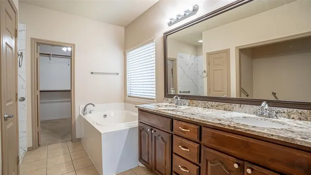 a bathroom with a granite countertop double vanity sink and mirror with shower
