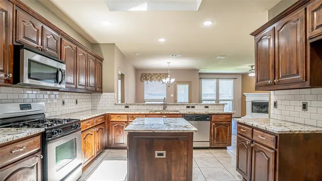a kitchen with stainless steel appliances granite countertop a stove top oven a sink dishwasher a dining table and chairs with wooden floor