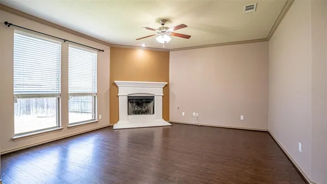an empty room with wooden floor fireplace and windows