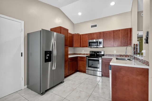 a kitchen with stainless steel appliances granite countertop a refrigerator and a stove top oven