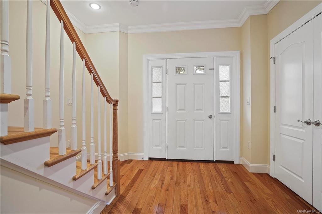 a view of front door with hallway and wooden floor