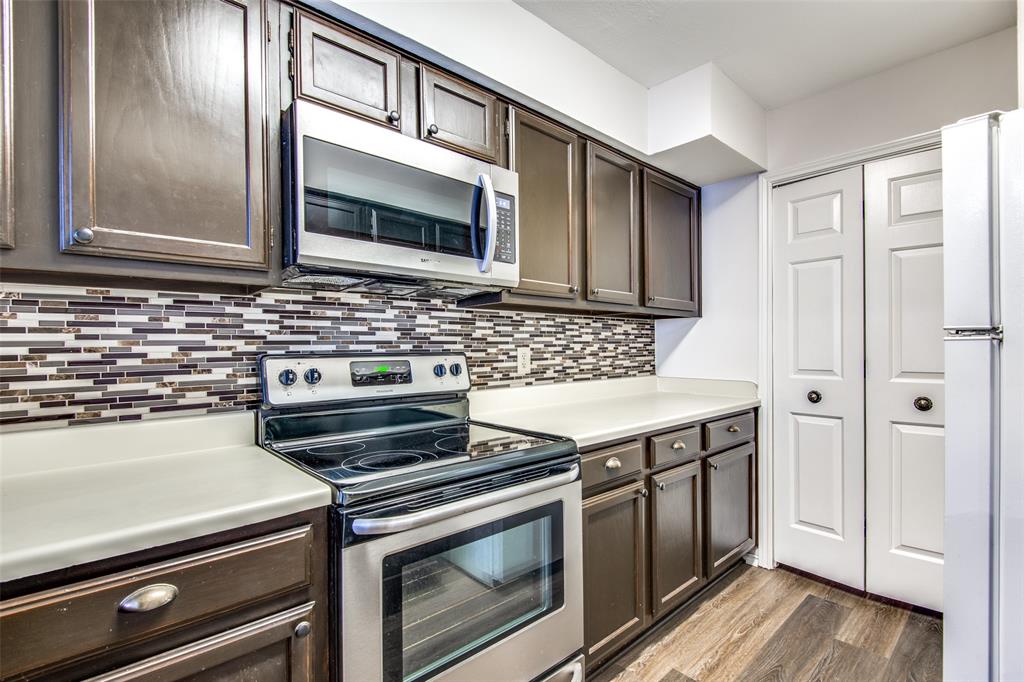 Kitchen featuring appliances with stainless steel finishes, dark brown cabinets, backsplash, and dark hardwood / wood-style floors