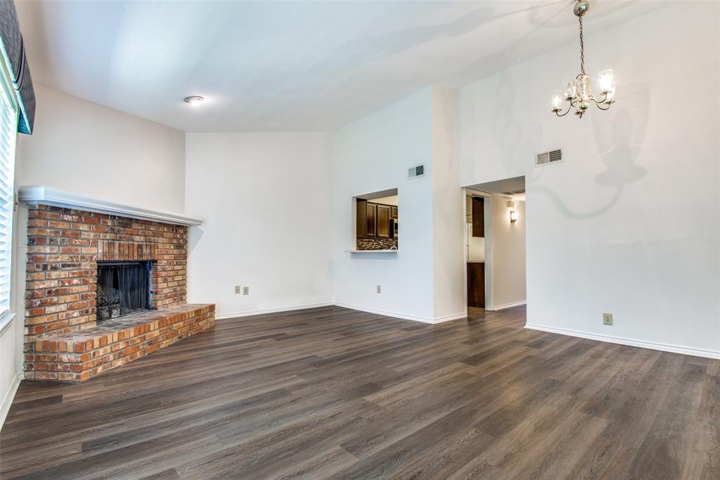 2835 Keller Springs Road, Unit 1304 Carrollton, TX 75006 - Photo 6 of 12 Unfurnished living room with high vaulted ceiling, dark hardwood / wood-style flooring, a brick fireplace, and a chandelier