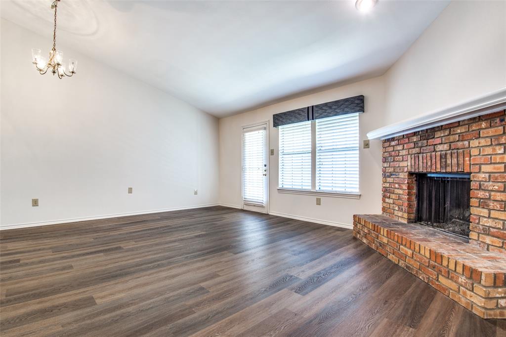 2835 Keller Springs Road, Unit 1304 Carrollton, TX 75006 - Photo 7 of 12 Unfurnished living room with a brick fireplace, a notable chandelier, dark hardwood / wood-style floors, and vaulted ceiling