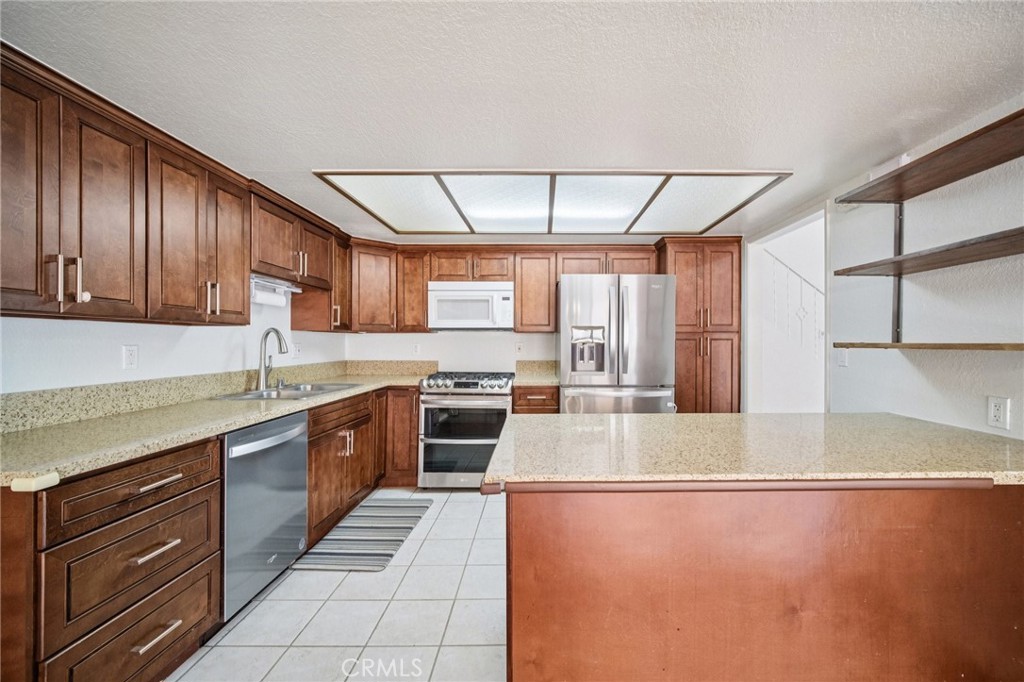 22810 Rio Chico Drive Valencia, CA 91354 - Photo 5 of 60 a large kitchen with stainless steel appliances granite countertop a sink stove and cabinets