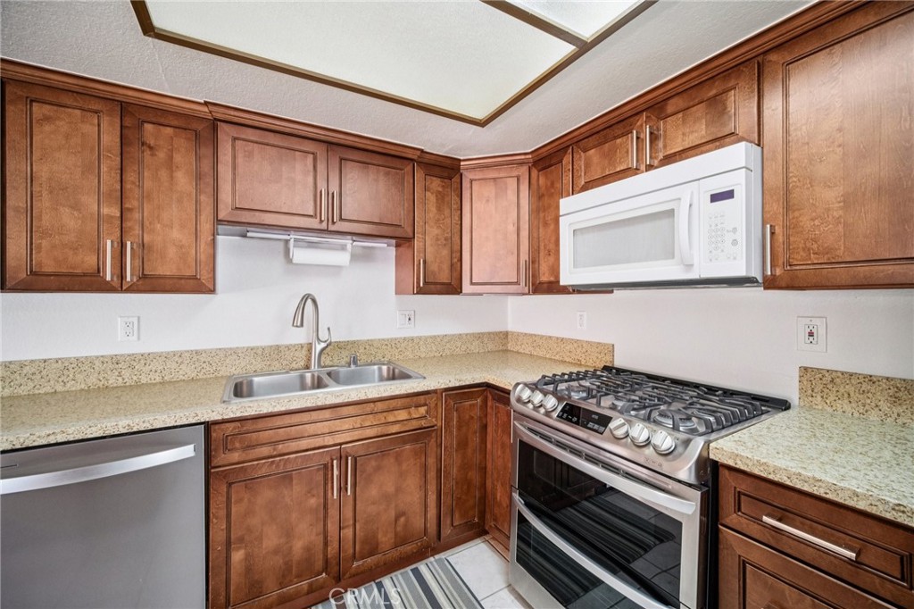 22810 Rio Chico Drive Valencia, CA 91354 - Photo 8 of 60 a kitchen with stainless steel appliances granite countertop a sink stove and microwave