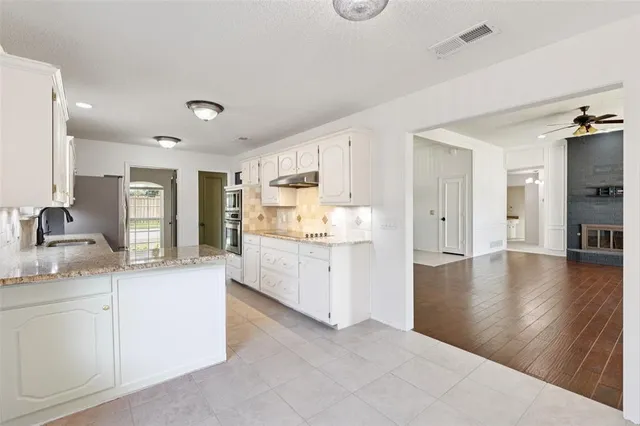 a kitchen with granite countertop a sink stainless steel appliances and white cabinets