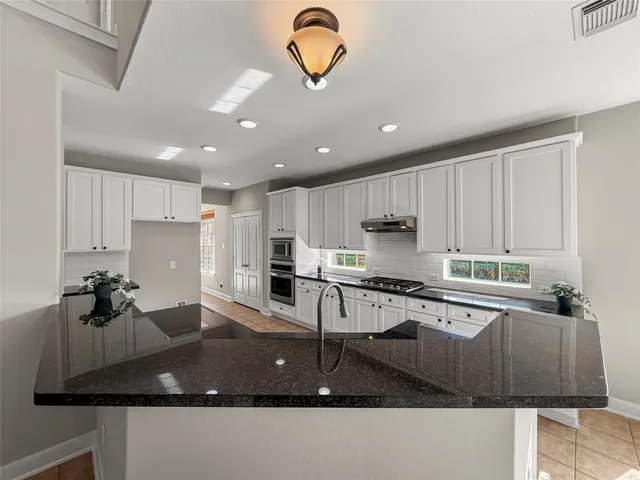 a kitchen with kitchen island granite countertop a stove a sink a refrigerator and a counter top space