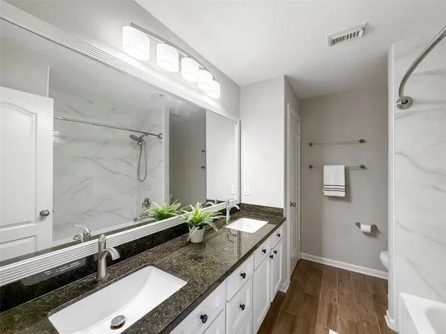 an empty room with wooden floor chandelier fan and windows