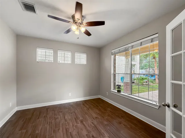 a view of an empty room with wooden floor and a window