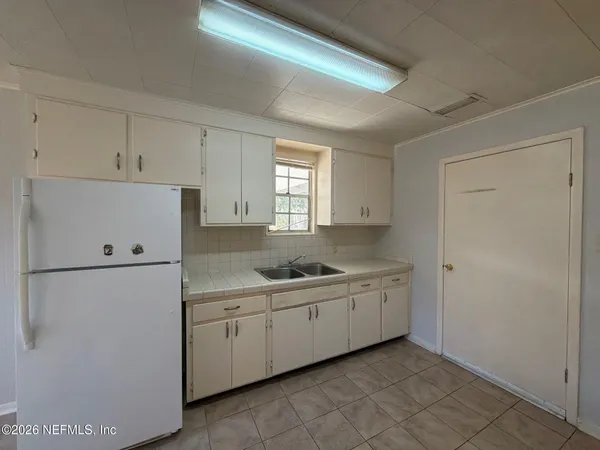 a kitchen with a sink a refrigerator and cabinets