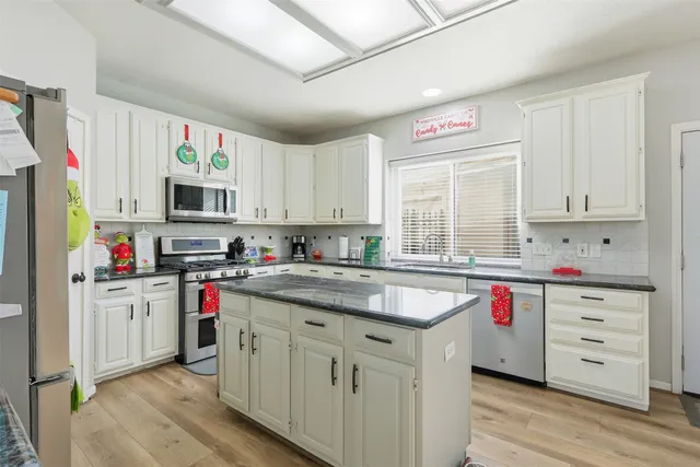 a kitchen with cabinets appliances a sink and a window