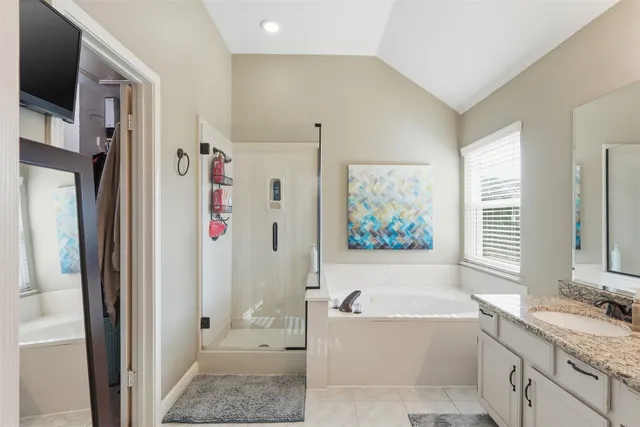 a bathroom with a granite countertop tub sink a window and a shower