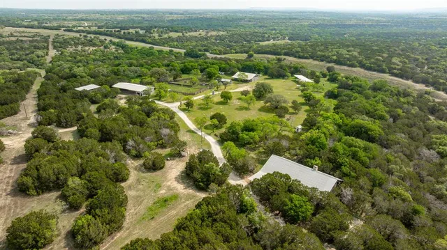 an aerial view of residential houses with outdoor space and trees