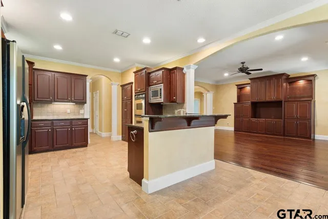 a large kitchen with stainless steel appliances kitchen island granite countertop a stove and a refrigerator