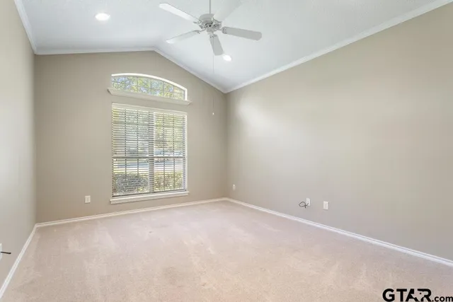 an empty room with a chandelier fan and windows