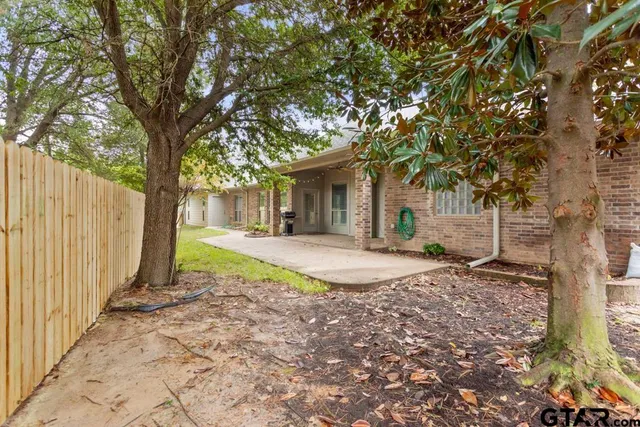 a view of a yard with wooden fence and a large tree