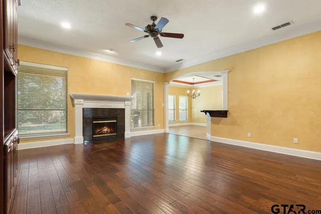 an empty room with wooden floor fireplace and a chandelier