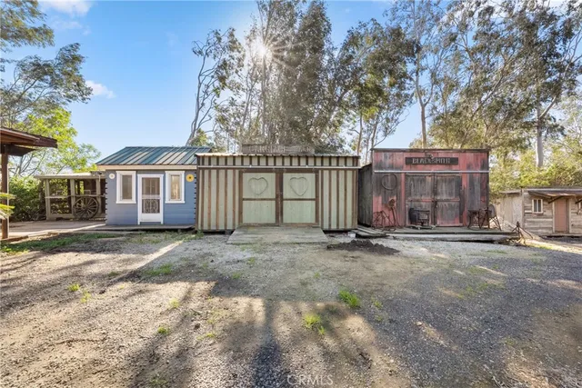 a view of a white house with a large tree and wooden fence