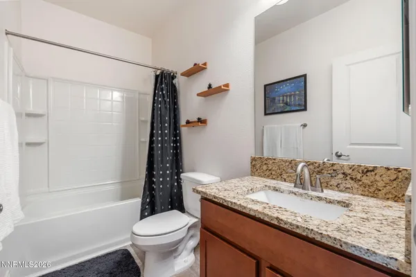 a bathroom with a granite countertop sink a toilet and shower