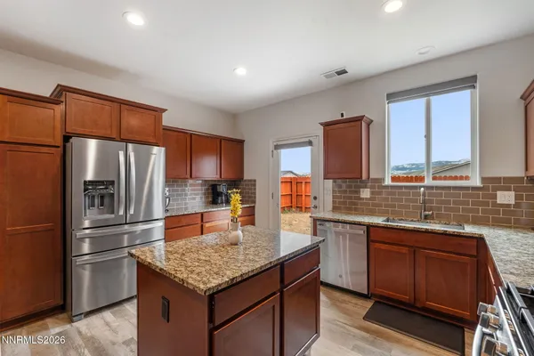 a kitchen with stainless steel appliances granite countertop a refrigerator a sink dishwasher a stove and white countertops with wooden floor