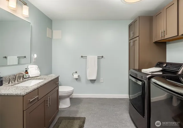 a bathroom with a granite countertop toilet sink and mirror