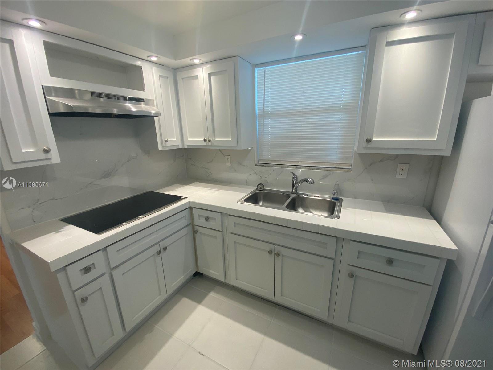 a kitchen with white cabinets sink and stove