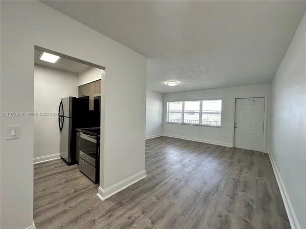 an empty room with wooden floor closet and windows