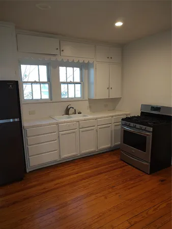 a kitchen with stainless steel appliances white cabinets and wooden floor