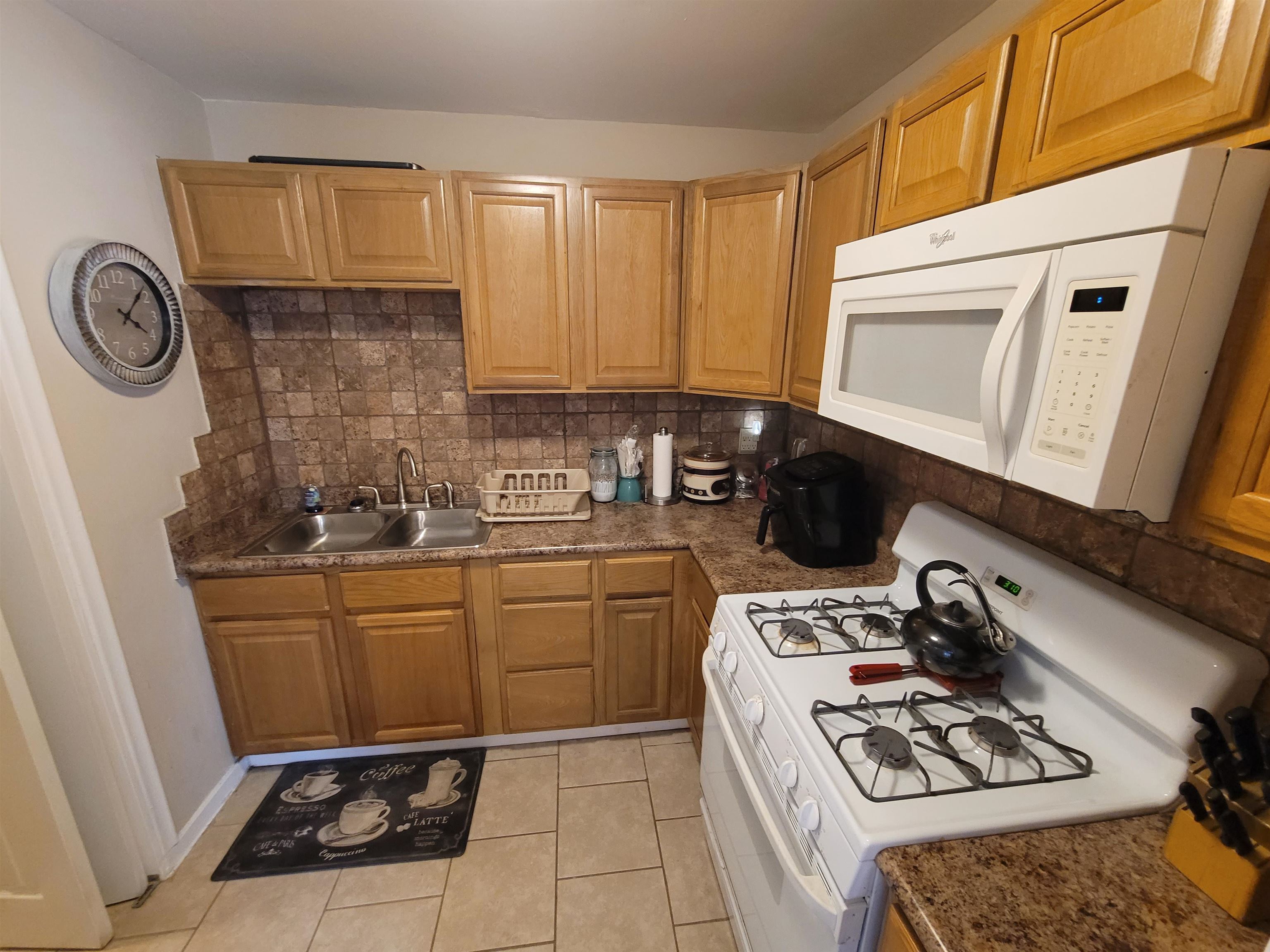 476 Jenson Road Memphis, TN 38109 - Photo 21 of 30 Efficient kitchen featuring light wood-finish cabinetry, a double basin stainless steel sink, a tile backsplash, and a built-in microwave above the range