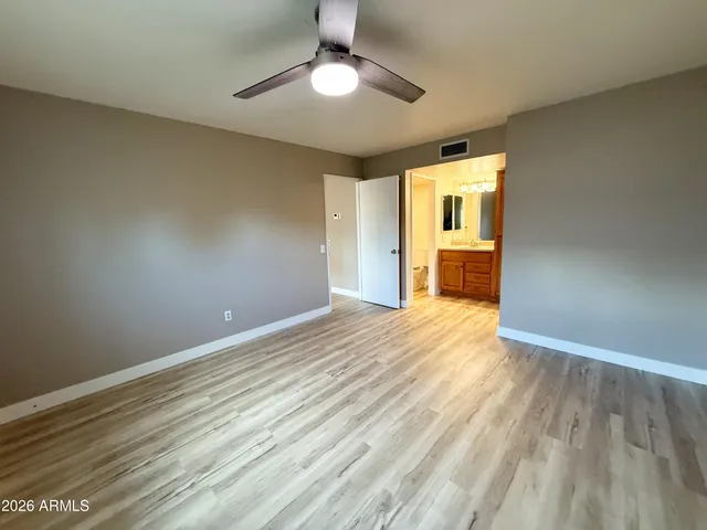 a view of empty room with wooden floor and fan