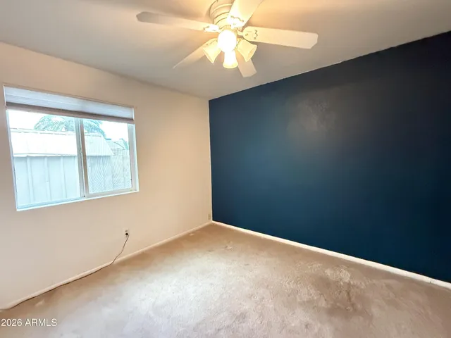 an empty room with a window and a fan