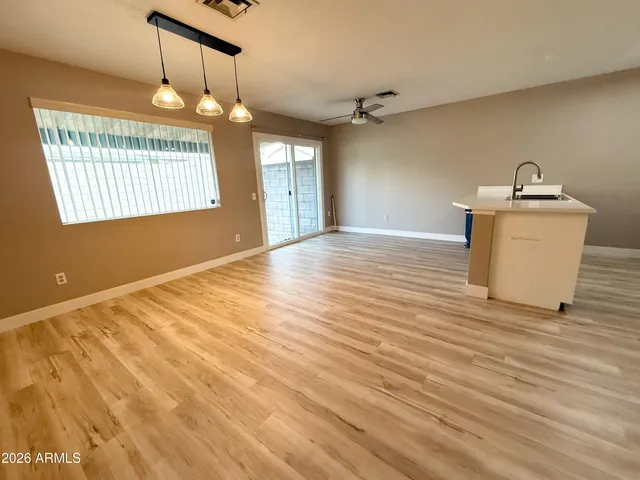a view of an empty room with window and wooden floor
