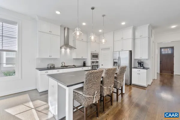 a kitchen with stainless steel appliances granite countertop sink refrigerator dining table and chairs