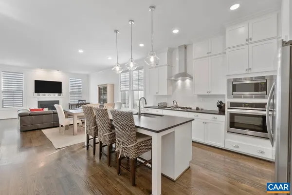 a kitchen with stainless steel appliances granite countertop a stove top oven a sink dishwasher a dining table and chairs with wooden floor