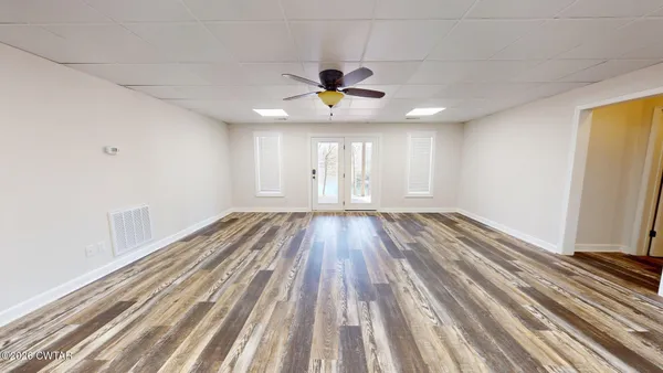 a view of a room with wooden floor ceiling fan and window