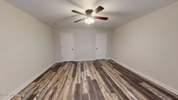 a view of a room with wooden floor and ceiling fan