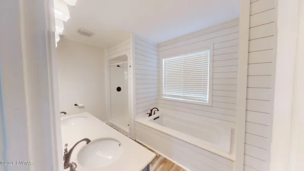 a bathroom with a tub sink and mirror