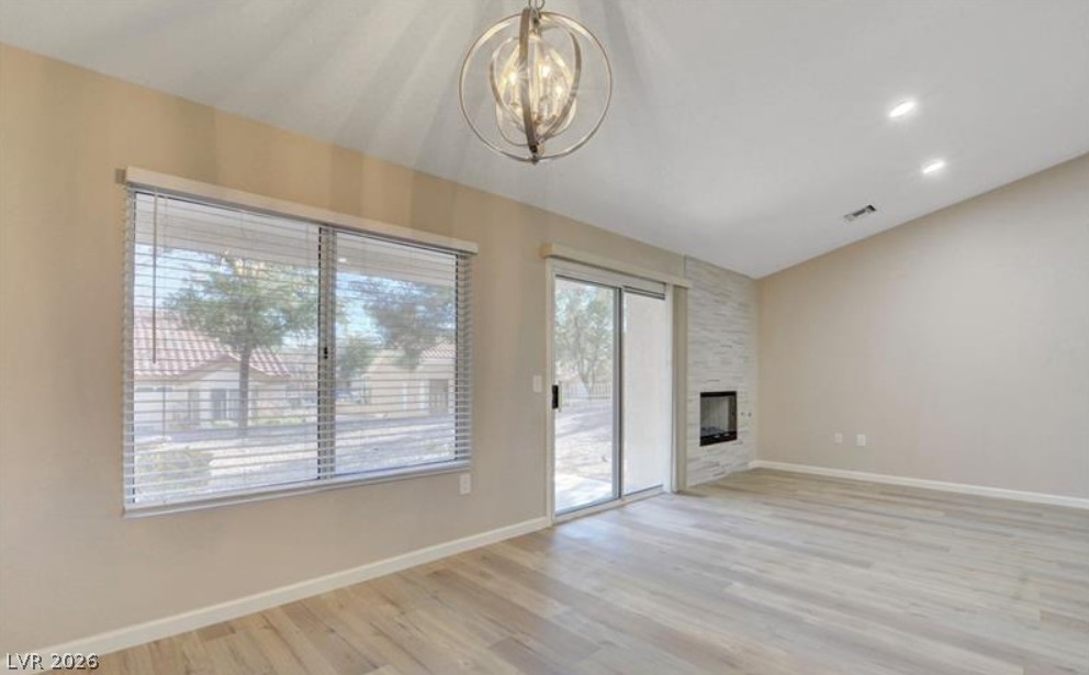 2716 Showcase Drive Las Vegas, NV 89134 - Photo 18 of 45 A living space offers light-colored wood flooring, a fireplace set in a stone wall, and a unique spherical chandelier.