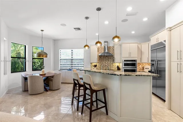 a kitchen with stainless steel appliances kitchen island granite countertop a table and chairs in it