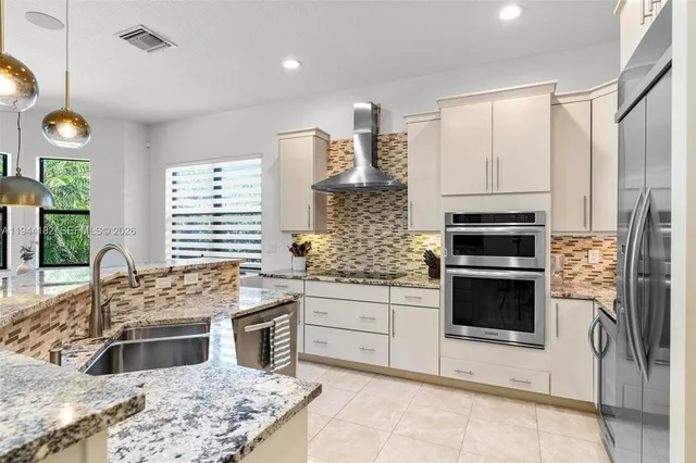 a kitchen with kitchen island granite countertop a sink cabinets and stainless steel appliances